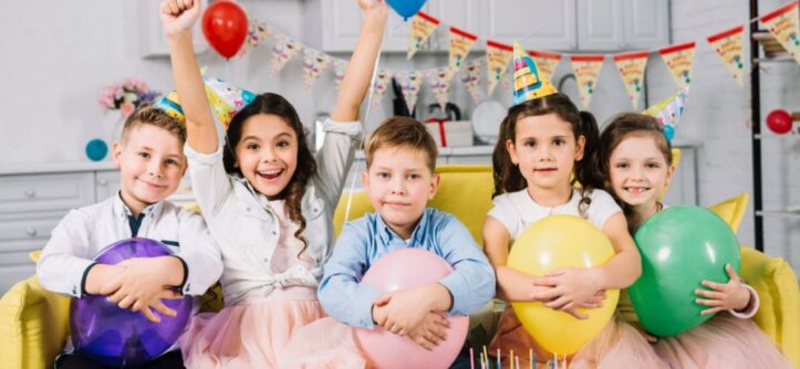 Children laughing and playing party games at colorful 8th birthday celebration with balloons and decorations