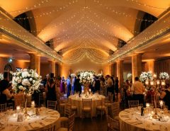 Warm uplighting illuminates stone columns in an elegant wedding reception ballroom.